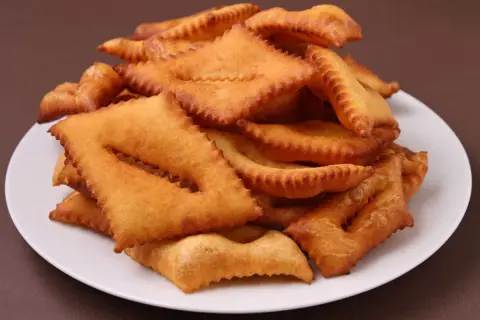 Une assiette de bugnes au four dorées et croustillantes, prêtes à être dégustées.