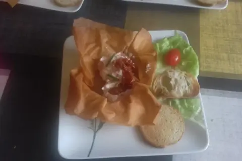 Une délicieuse grolle recette : une coupe de pâte filo garnie de fromage frais, tomates séchées et ciboulette, servie avec des toasts et une feuille de laitue.