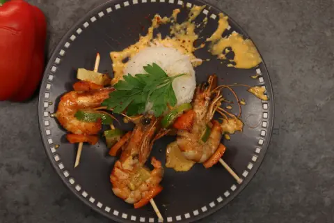 Brochettes de crevettes au chorizo et crème, servies avec du riz blanc et des poivrons.