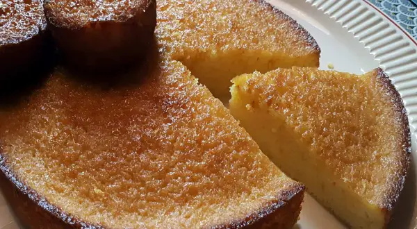 Un délicieux gâteau à l'orange, avec une croûte dorée et une mie moelleuse, servi sur une assiette blanche.