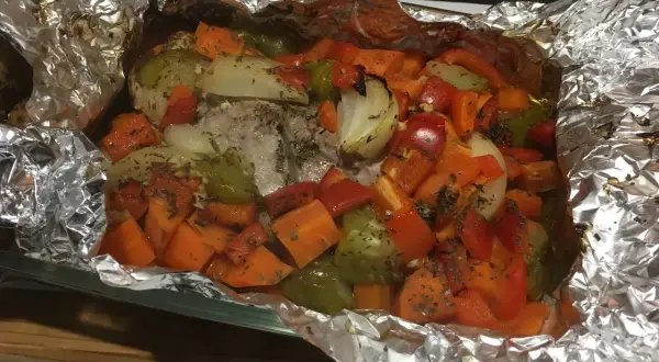 Filet mignon en papillote aluminium, cuit avec des légumes colorés comme des carottes, poivrons et oignons. Un plat savoureux et sain.
