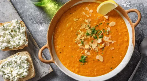 Soupe égyptienne onctueuse, garnie d'amandes effilées et de persil frais, avec une tranche de citron. Accompagnée de toasts au fromage frais.