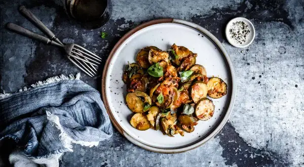 Assiette de courgettes sautées, tomates et basilic frais, parfaite pour une recette basilic simple et savoureuse.