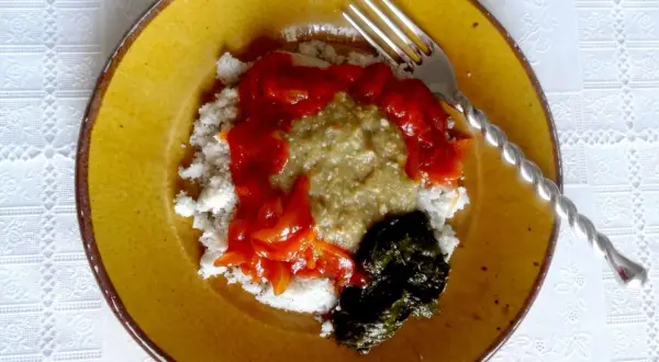 Un plat guinéen facile : riz blanc, sauce verte, sauce tomate et feuilles de manioc sur une assiette jaune.