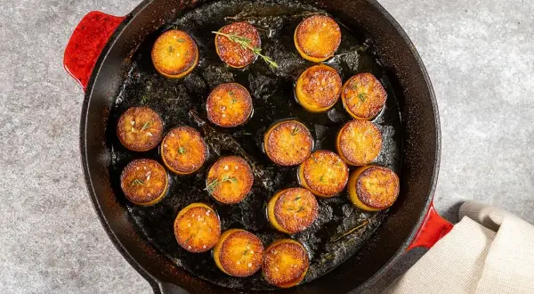 Pommes de terre en sauce brune, dorées et savoureuses, mijotent dans une poêle en fonte avec des herbes aromatiques.