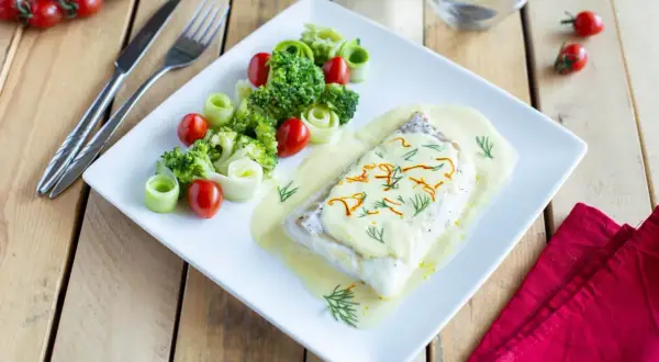 Dos de cabillaud au four, nappé d'une sauce onctueuse au vin blanc et crème fraîche, accompagné de brocolis, tomates cerises et rouleaux de concombre.