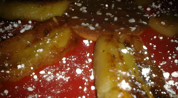 Délicieuse banane grillée à la poêle, saupoudrée de sucre glace, sur une assiette rouge. Un dessert gourmand et simple.