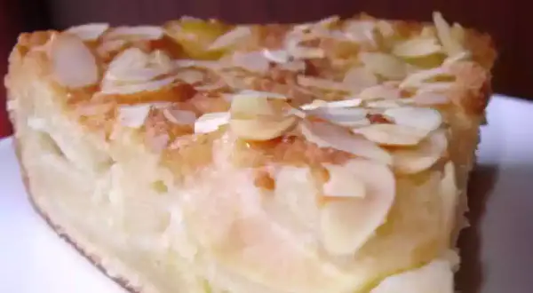 Une part de gâteau d'Ève, aux pommes et amandes effilées, dorée et appétissante.