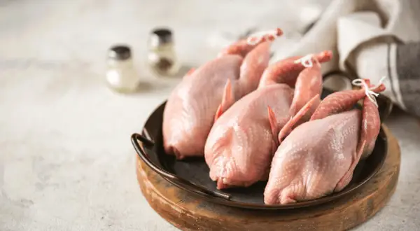 Trois cailles crues, prêtes pour une savoureuse sauce chasseur.