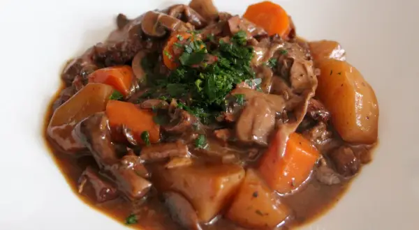 Un savoureux bourguignon végétarien avec des champignons, des carottes et des pommes de terre, garni de persil frais.