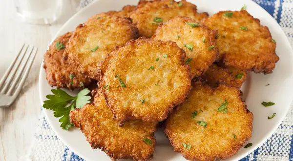 Assiette de beignets de brimbelle dorés, parsemés de persil frais. Un délice croustillant !