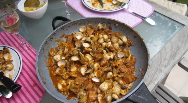 Plat de fruits de mer et porc mijoté dans une sauce savoureuse, prêt à être dégusté. Une recette cataplana porc et fruits de mer qui met l'eau à la bouche.