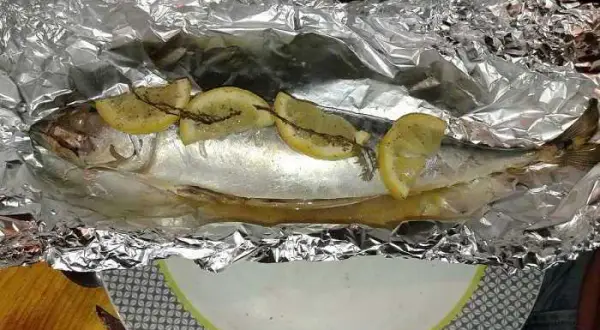 Maquereau entier, prêt à être cuit en papillote au barbecue, garni de rondelles de citron et d'herbes.