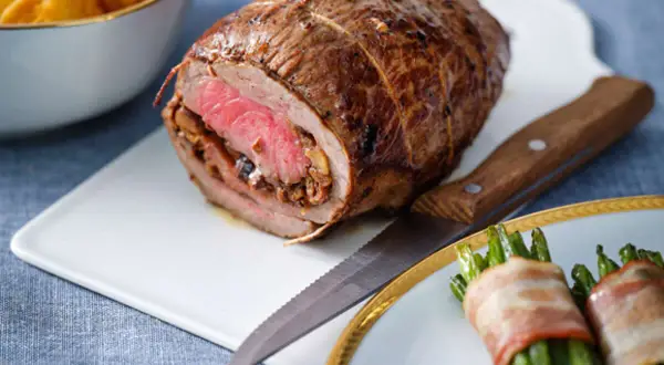 Un rôti de bœuf farci, prêt à être découpé, évoque une délicieuse recette rosbif alsacien. Accompagné de haricots verts enroulés de lard.