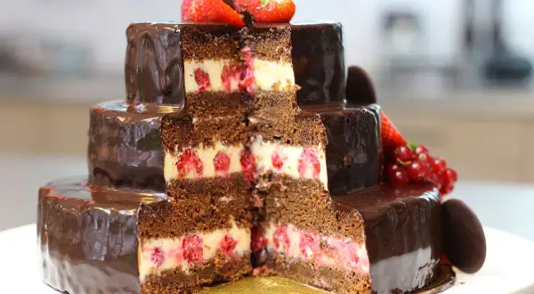 Gâteau à trois étages, chocolaté et garni de framboises, décoré de fraises et de groseilles. Un délice pour les yeux et les papilles, ce gâteau Christine est une œuvre d'art.