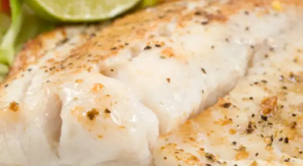Filet de turbot au four en papillote, tendre et savoureux, servi avec une tranche de citron vert et des légumes croquants.