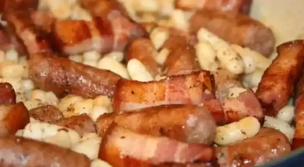 Saucisses catalanes enveloppées de lard, mijotant avec des haricots blancs. Une recette savoureuse à découvrir.