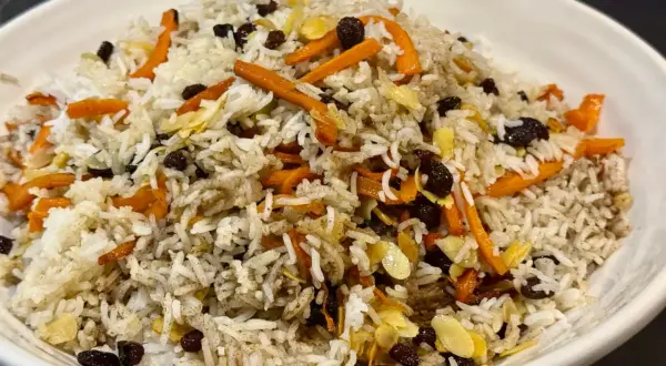 Un plat de riz parfumé, garni de carottes râpées, de raisins secs et d'amandes effilées. Une belle présentation de la recette riz afghan.