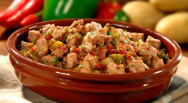 Un plat d'axoa de veau, mijoté avec des poivrons et des oignons, servi dans un bol en terre cuite. Parfait pour savoir si on peut préparer un axoa de veau la veille.