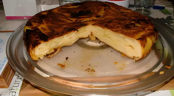 Une délicieuse farinette aux pommes, dorée et moelleuse, servie sur un plat en verre. Un vrai régal !