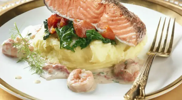 Filet de saumon sur purée, garni d'épinards et tomates, nappé d'une délicieuse sauce crevette. Un plat savoureux.