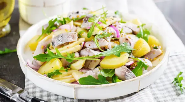 Salade de pommes de terre et hareng frais à la poêle, garnie de roquette et d'oignons rouges. Une recette simple et savoureuse.