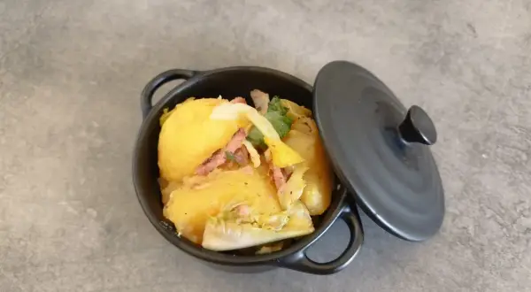 Un plat de pommes de terre et lardons, rappelant la recette ardennaise de nos grands-mères, servi dans une cocotte noire.