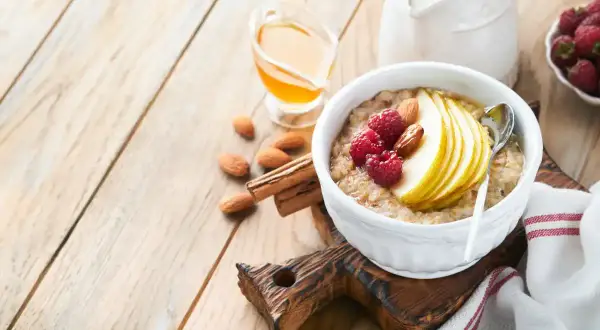 Délicieuse bouillie bretonne garnie de fruits rouges, poire et amandes, avec du miel et du lait à côté.