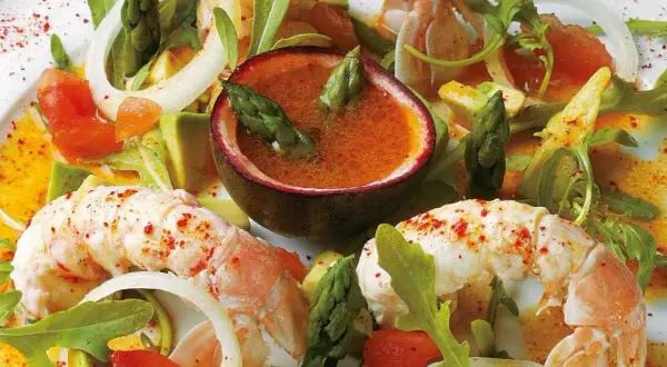 Salade de langouste aux agrumes et avocat, avec asperges et fruits de la passion. Un plat frais et coloré.