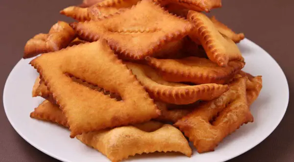 Une assiette de bugnes au four dorées et croustillantes, prêtes à être dégustées.
