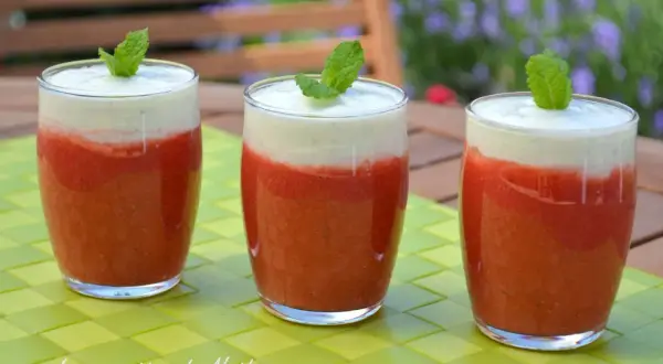 Trois verres de soupe fraise menthe, garnie d'une feuille de menthe, sur une table verte.