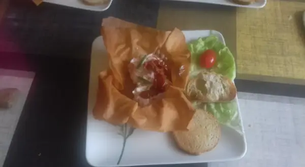 Une délicieuse grolle recette : une coupe de pâte filo garnie de fromage frais, tomates séchées et ciboulette, servie avec des toasts et une feuille de laitue.