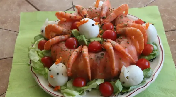 Couronne aux deux saumons, décorée de crevettes, tomates cerises, œufs durs en forme de poulets et de lapins, sur un lit de salade.