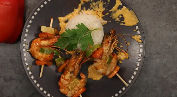 Brochettes de crevettes au chorizo et crème, servies avec du riz blanc et des poivrons.