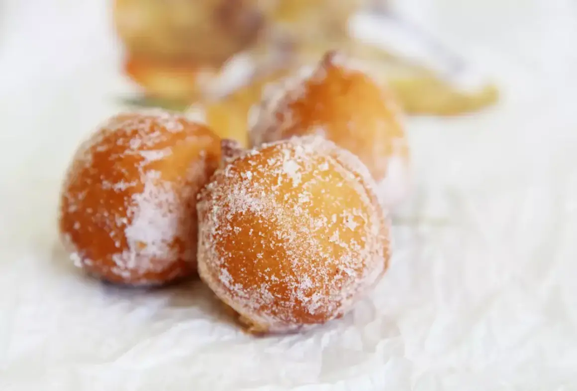 Trois beignets dorés, saupoudrés de sucre, évoquant un délicieux dessert de Côte d'Ivoire.