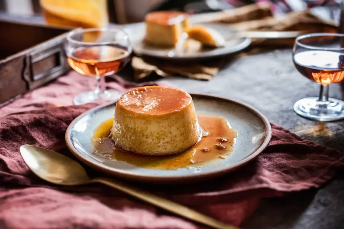 Un délicieux dessert croate recette, un flan caramélisé, servi sur une assiette avec une cuillère dorée et un verre de liqueur ambrée.