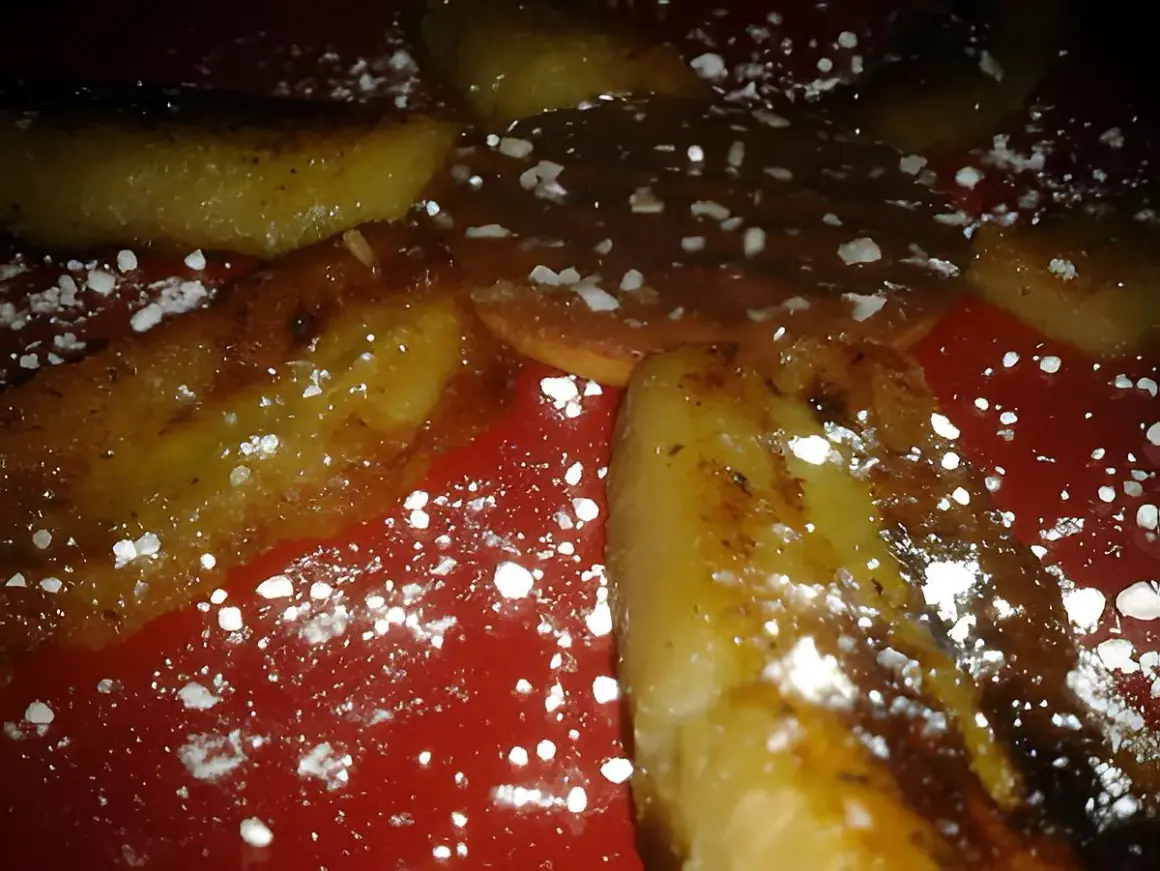 Délicieuse banane grillée à la poêle, saupoudrée de sucre glace, sur une assiette rouge. Un dessert gourmand et simple.