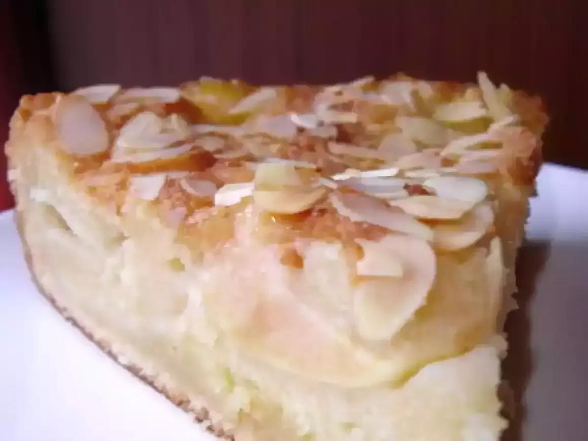 Une part de gâteau d'Ève, aux pommes et amandes effilées, dorée et appétissante.