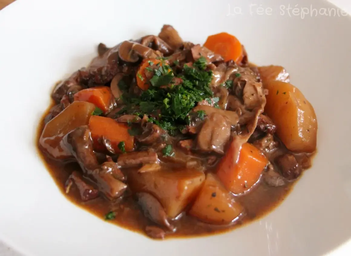 Un savoureux bourguignon végétarien avec des champignons, des carottes et des pommes de terre, garni de persil frais.