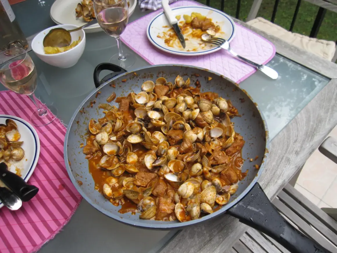 Plat de fruits de mer et porc mijoté dans une sauce savoureuse, prêt à être dégusté. Une recette cataplana porc et fruits de mer qui met l'eau à la bouche.