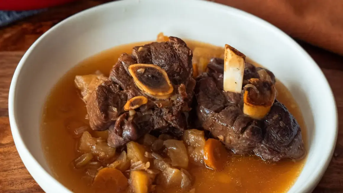 Un plat réconfortant de jarret de cerf mijoté avec des carottes et des pommes de terre dans un bouillon savoureux.