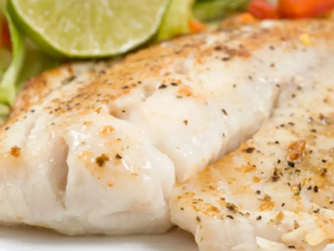 Filet de turbot au four en papillote, tendre et savoureux, servi avec une tranche de citron vert et des légumes croquants.