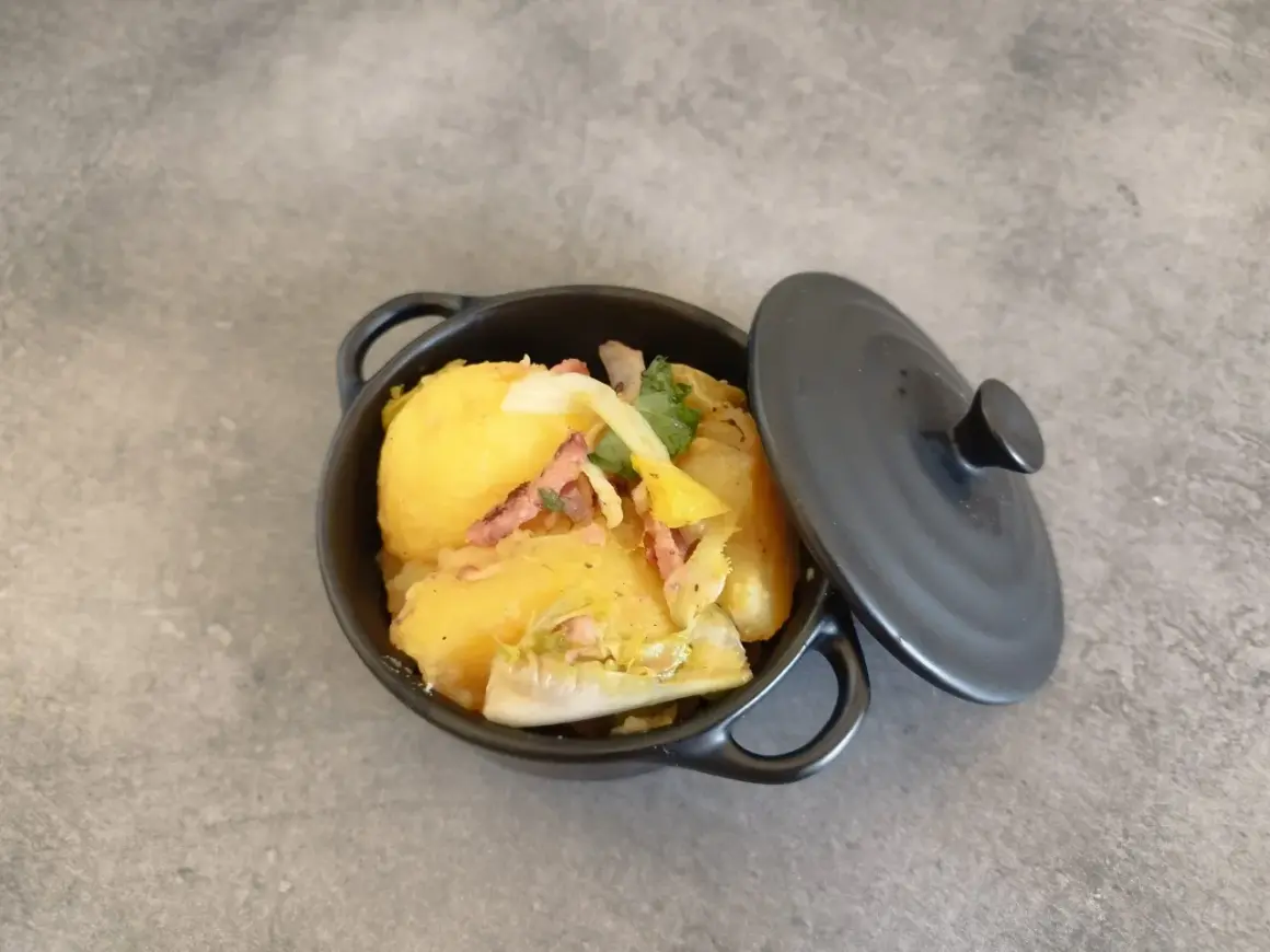 Un plat de pommes de terre et lardons, rappelant la recette ardennaise de nos grands-mères, servi dans une cocotte noire.
