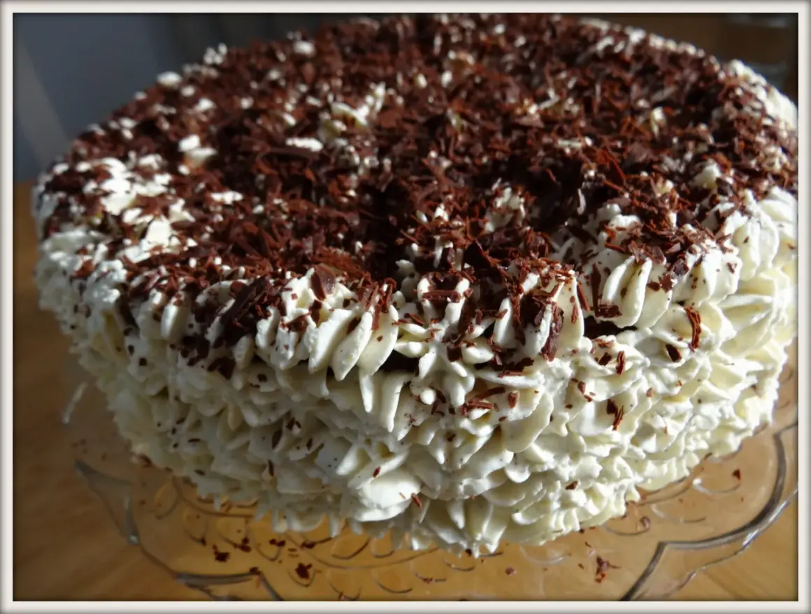 Gâteau noir en chemise de crème fouettée et copeaux de chocolat.
