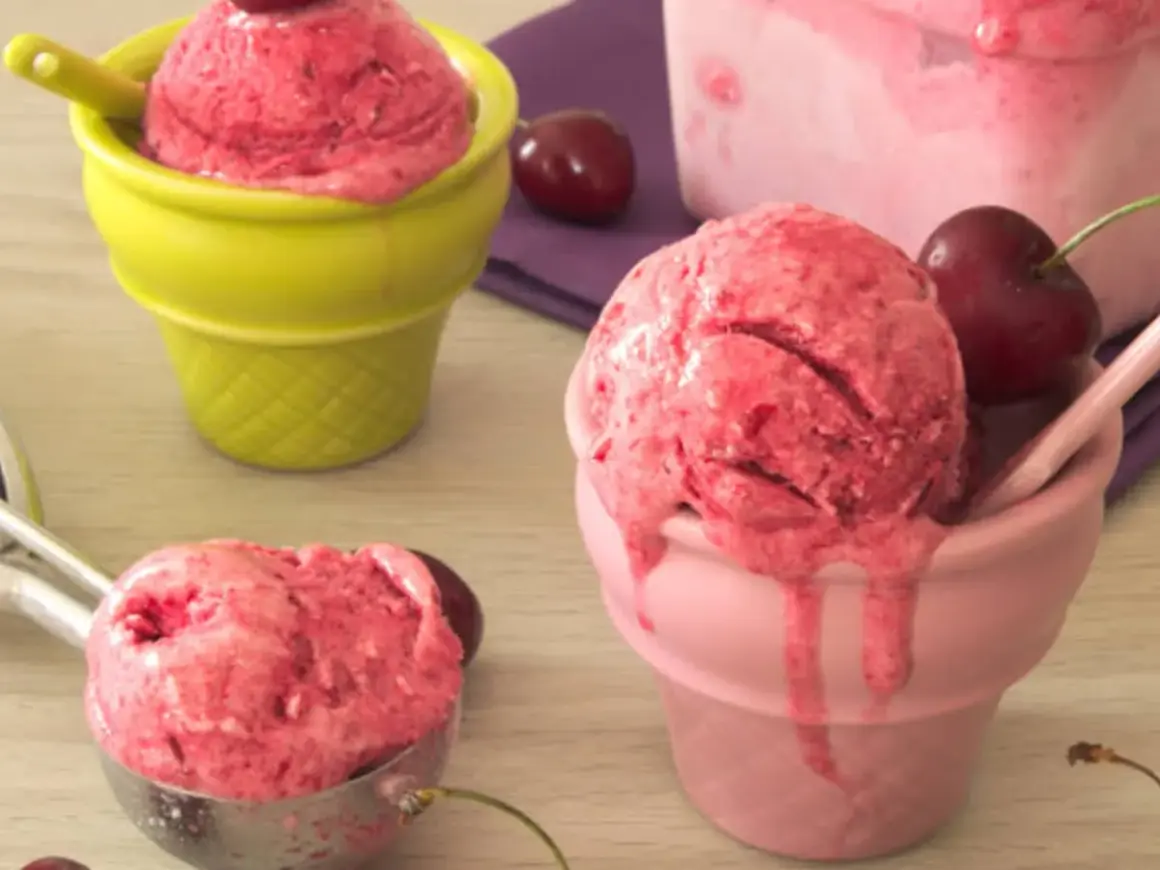 Trois coupes colorées servent une délicieuse recette sorbet cerise, avec des cerises fraîches et une cuillère à glace.