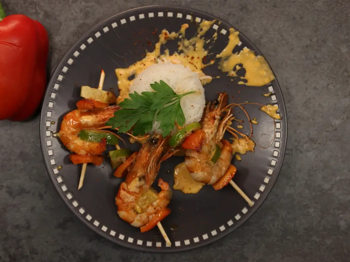Brochettes de crevettes au chorizo et crème, servies avec du riz blanc et des poivrons.