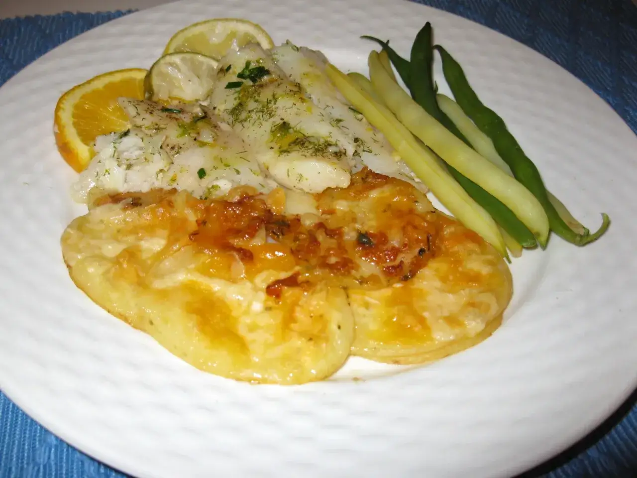 Délicieux filet de turbot au four en papillote, servi avec des pommes de terre gratinées et des haricots verts.