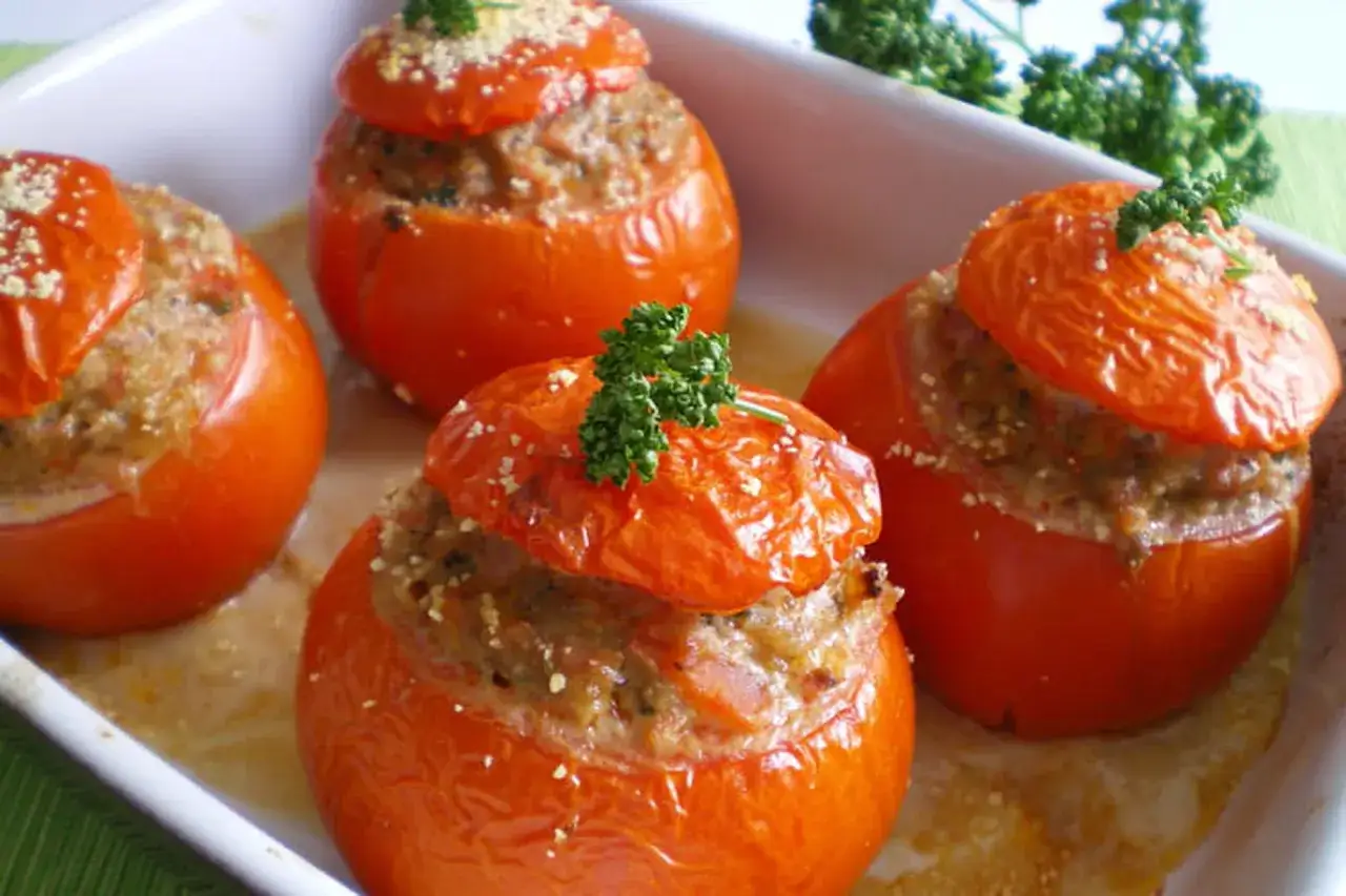 Tomates farcies à la viande, prêtes pour le temps de cuisson. Garnies de persil frais et de chapelure.
