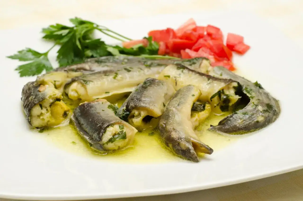 Délicieux rouleaux d'anguille farcis aux herbes, baignant dans une sauce dorée. Une recette simple pour comment préparer une anguille.