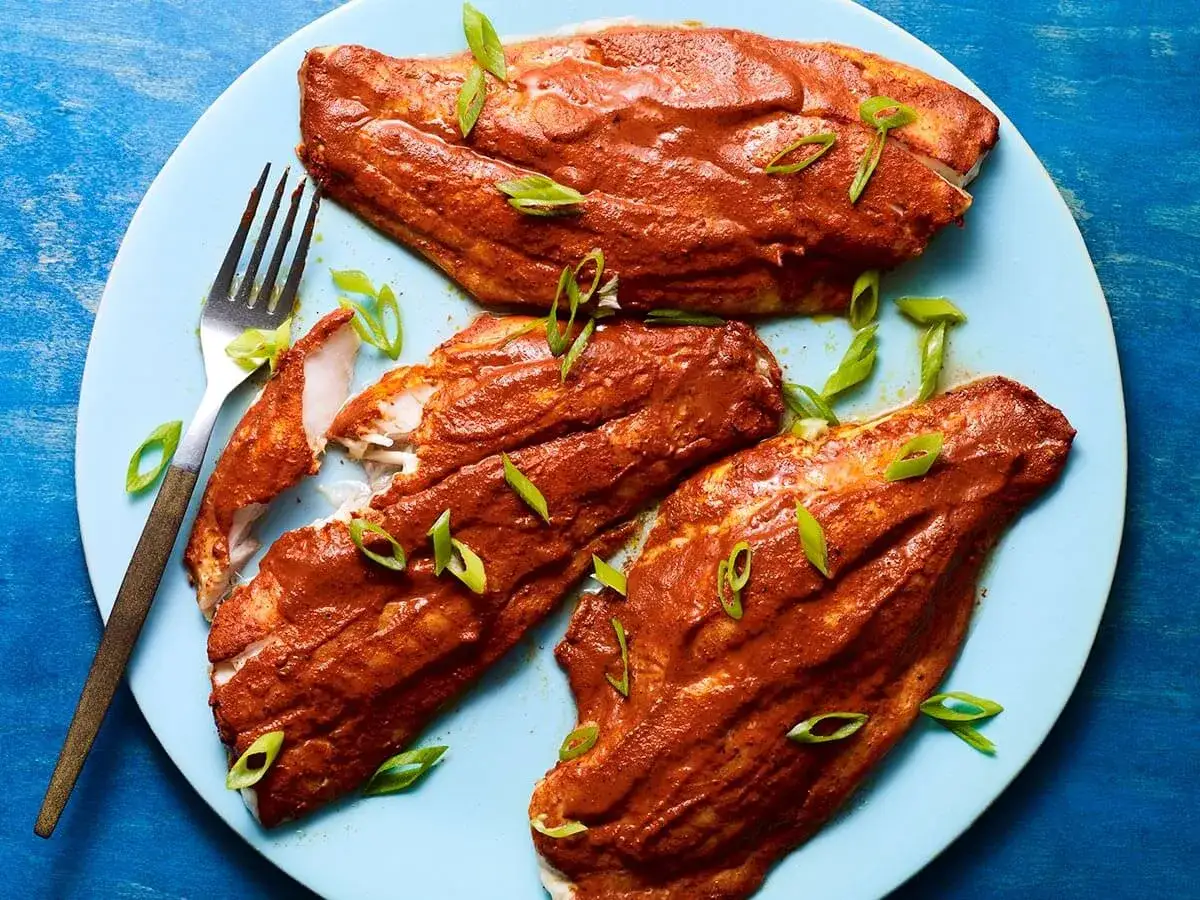 Trois filets de poisson napp&eacute;s d'une sauce rouge &eacute;pic&eacute;e, parsem&eacute;s de ciboule. Une recette de beurre rouge antillais &agrave; d&eacute;couvrir.
